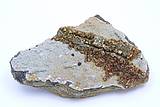 Abb. zeigt eine Pyrit Markasitstufe, auf weißem Calcit zieht sich wie ein Gebirge ein Kam von hochglänzenden goldfarbigen schilernden Kristalle.