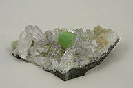 Abb. einer Bergristallstufe von 12 cm und sehr reinen Kristallen, mitendrinn sitzt ein hellgrüne Kugel von Prehnit mit 2 cm Größe