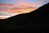 Sonnenaufgang im Vordergrund die Zelte im Hintergrund der Himmel mit Wolken die orange gefärbt sind.