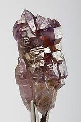 Abb. Zeigt einen 6,8 x 3,5 cm großen Amethyst der blockartig verwachsen ist, das Wechselspiel von glänzenden Kristallflächen und Schatten sticht dabei besonders hervor.